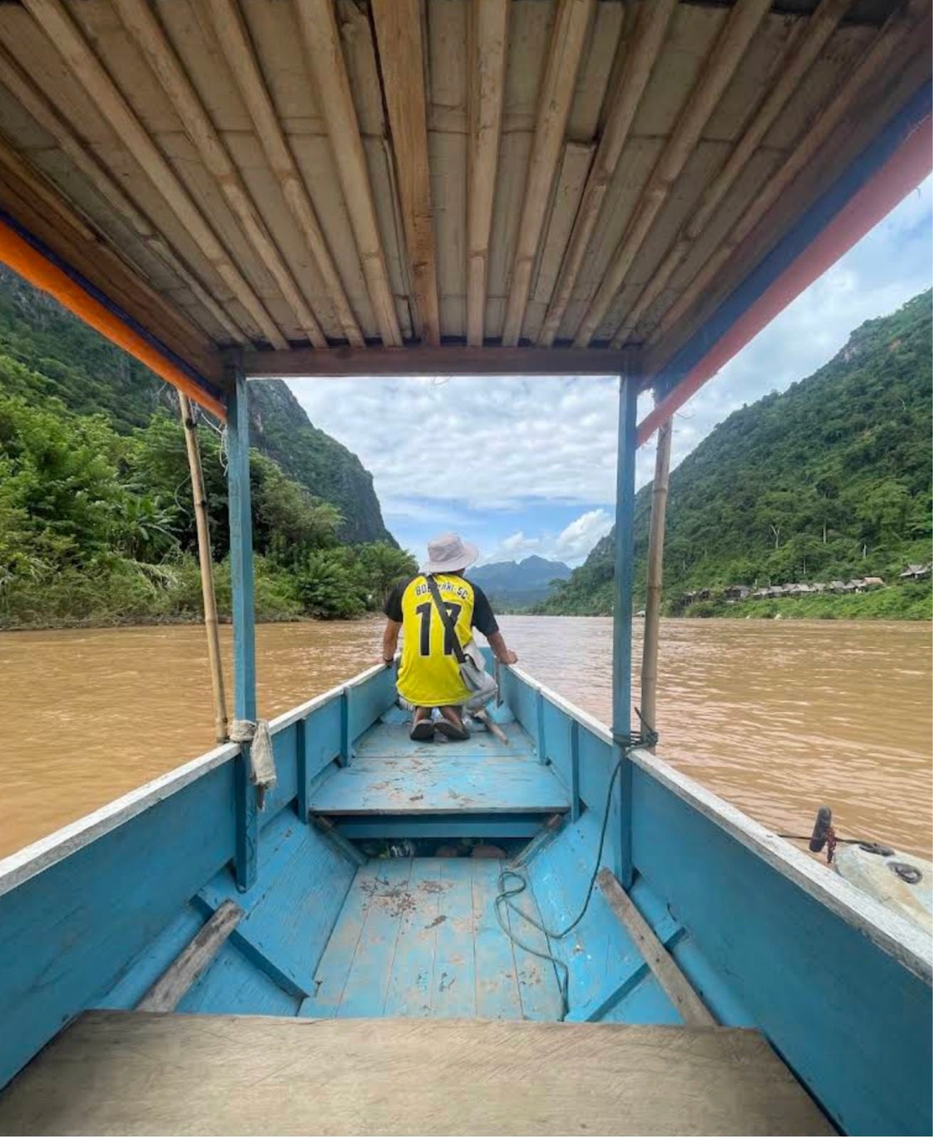 View from inside a wooden boat on the brown Nam Ou river