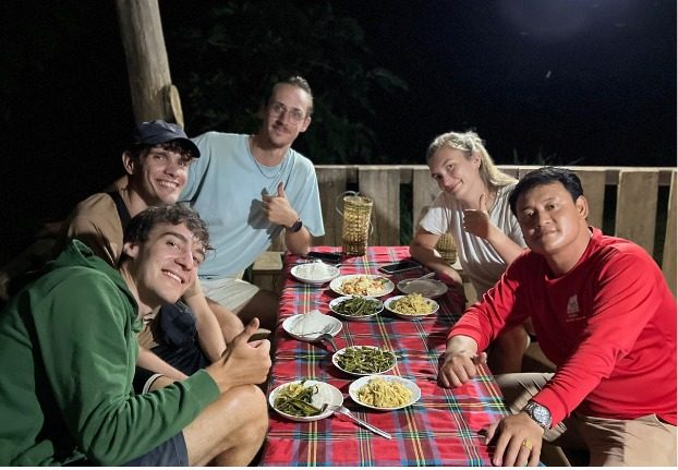 Guests and a guide sharing a Lao dinner at night