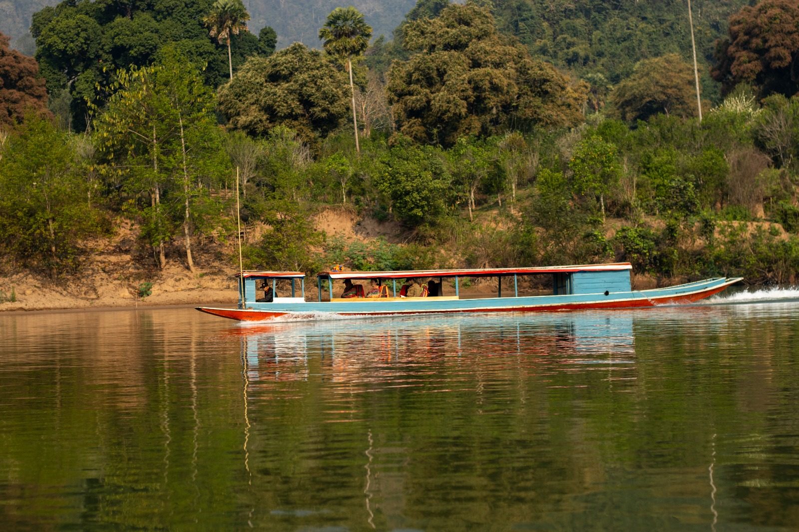 A blue long-tail boat on calm green water